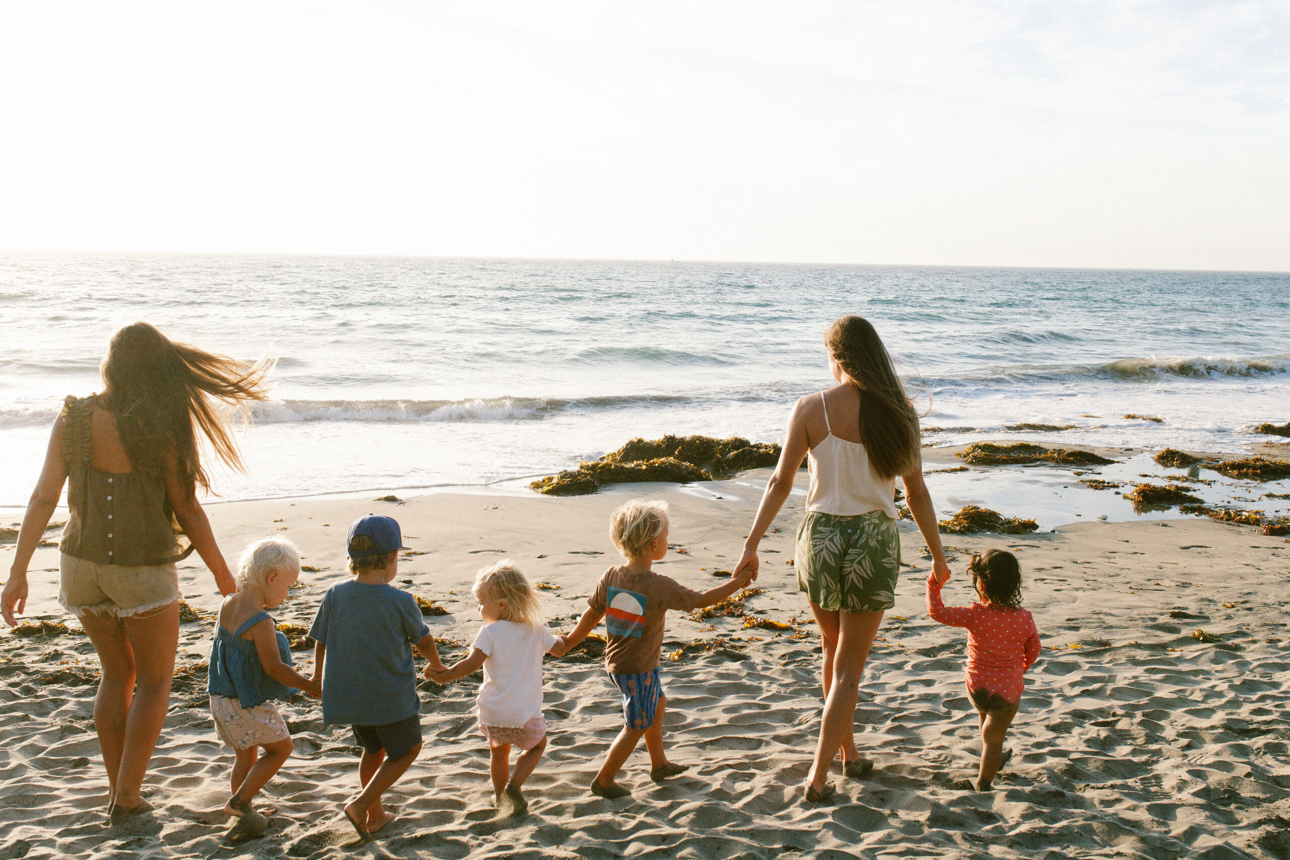 Two mothers walking five children hand in hand toward the ocean